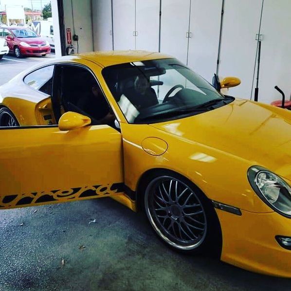 Yellow Porsche sports car with door open, parked indoors.