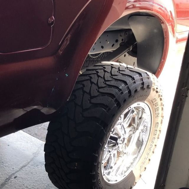 Close-up of a red vehicle's wheel with a chrome rim and a large, rugged tire.