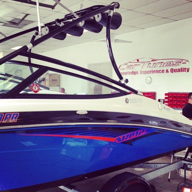 Blue and white boat with black accents and speakers mounted on a tower inside a shop.