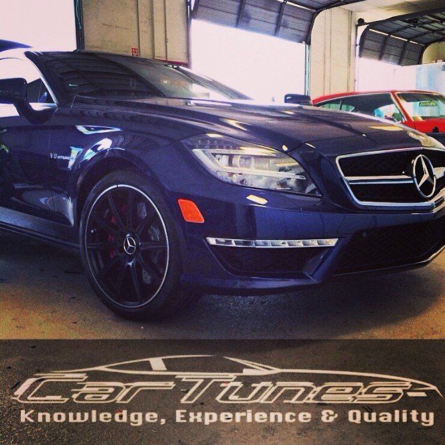 Dark blue Mercedes-Benz CLS in a garage with black rims. Car Tunes logo in foreground.