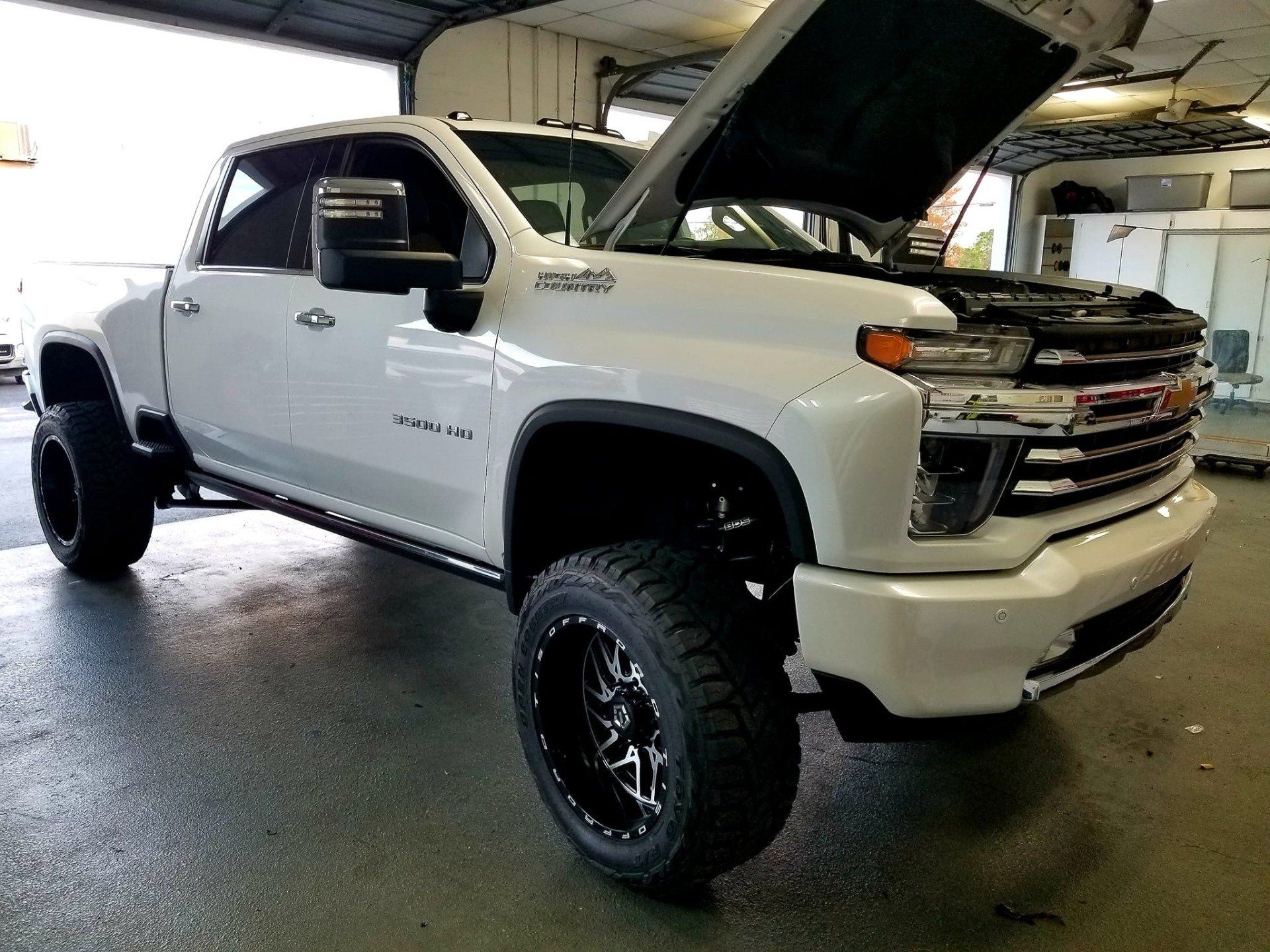 White Chevrolet truck with the hood open in a garage.