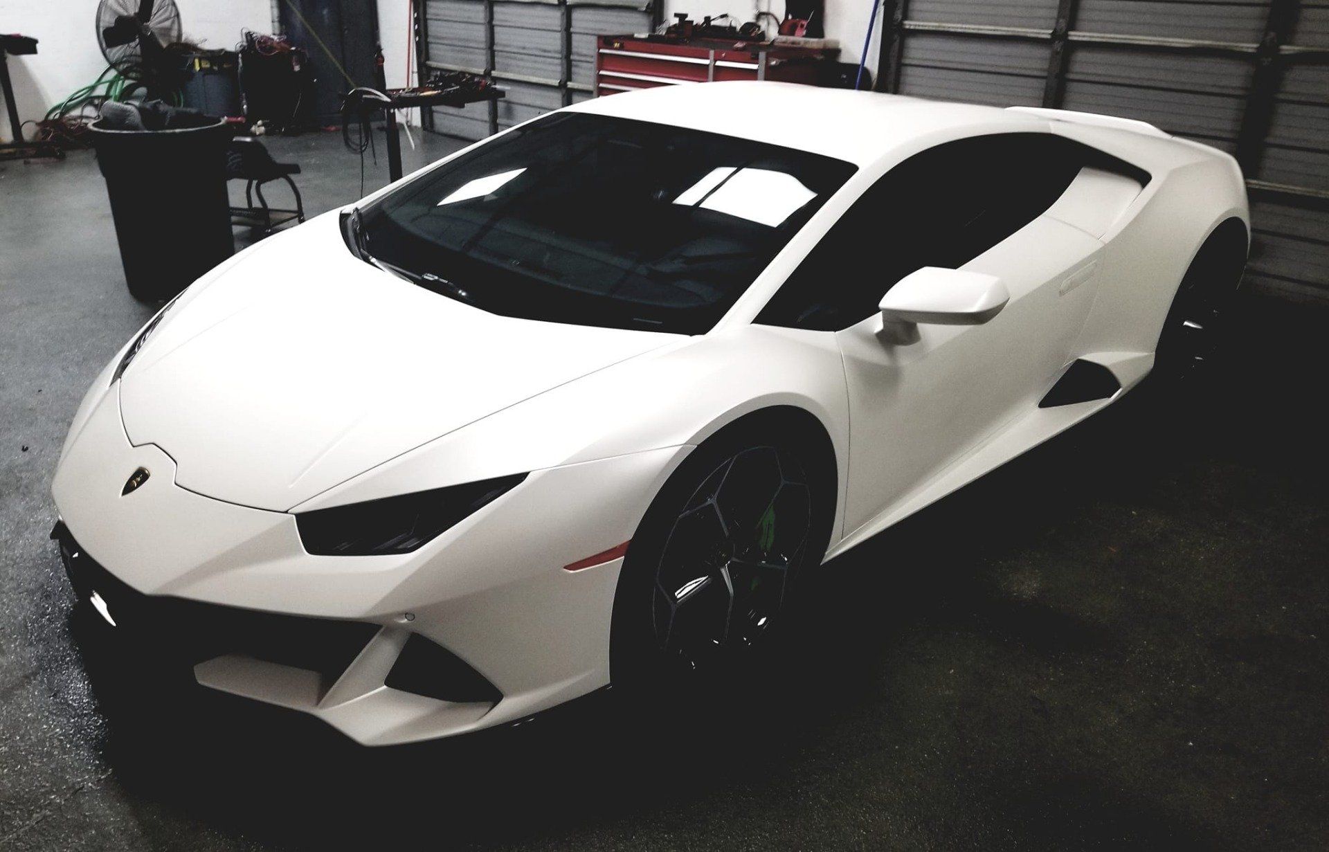 White Lamborghini parked in a garage with dark tinted windows.