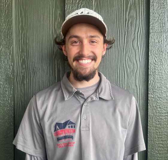 A man wearing a hat and a grey shirt is smiling