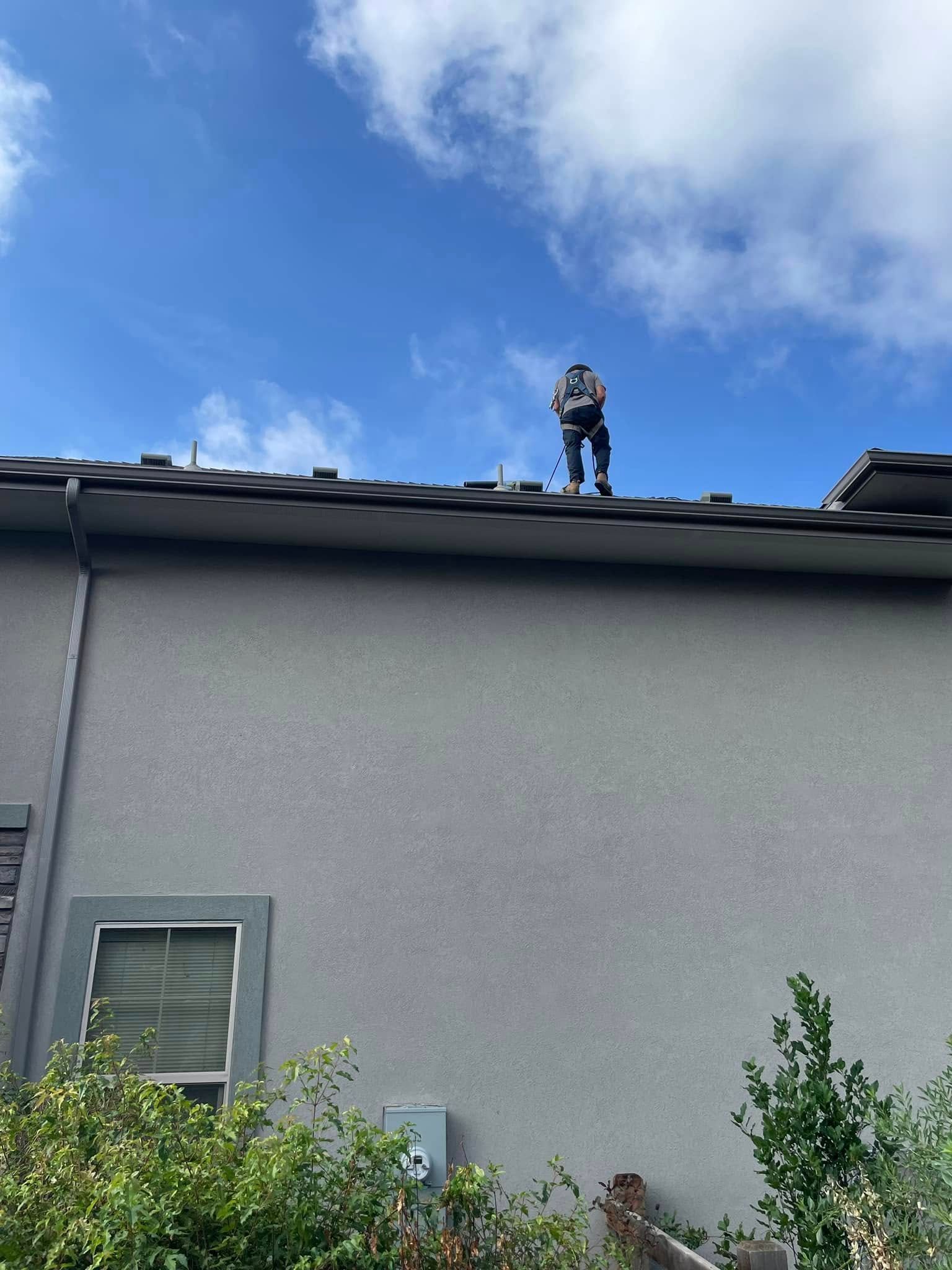 A man is standing on the roof of a house.