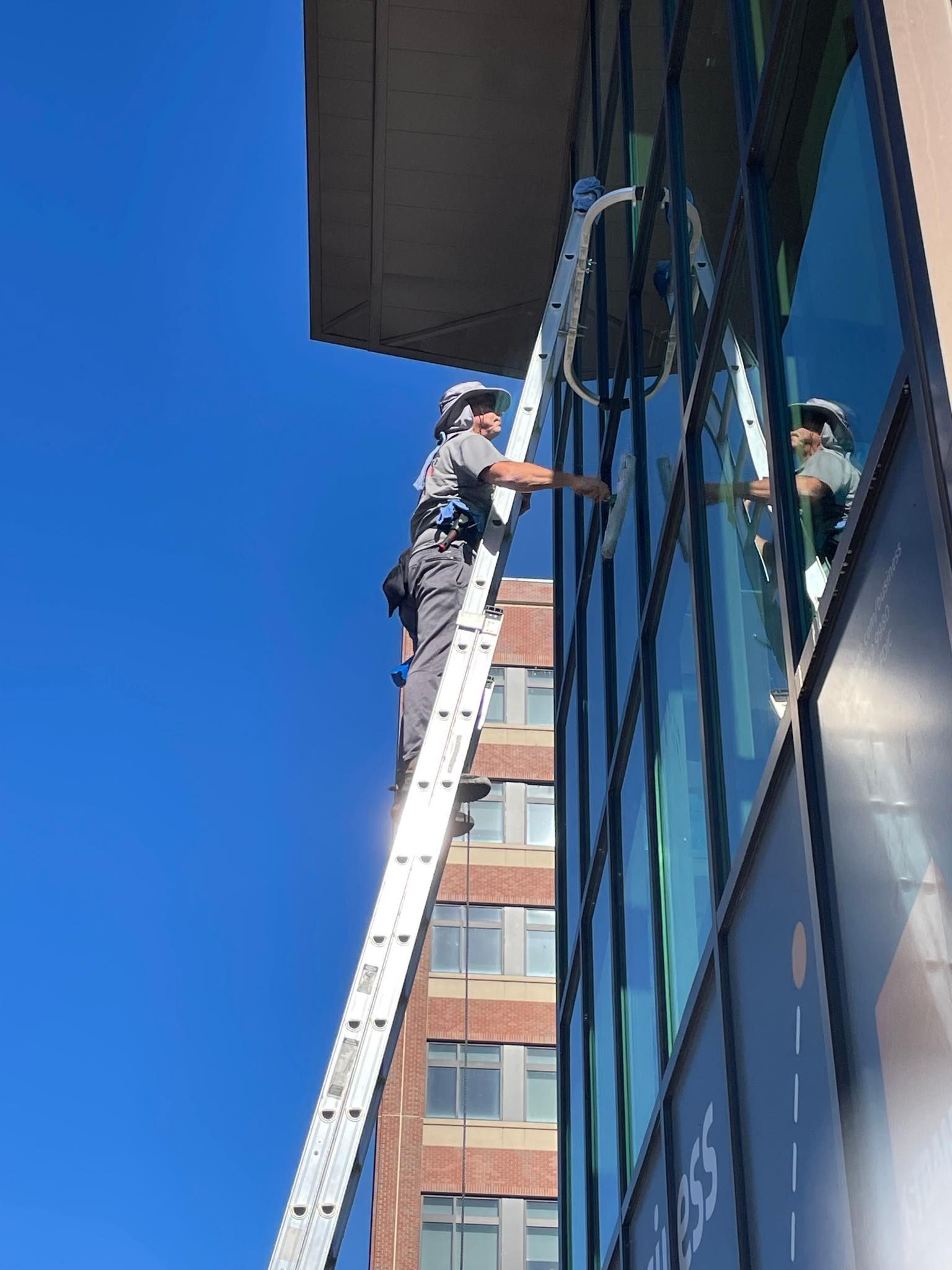 A man is standing on a ladder cleaning a building 's windows.