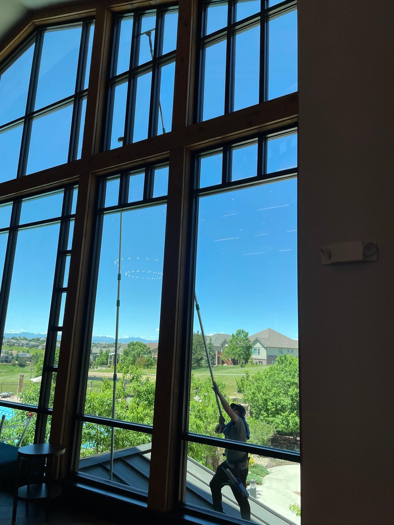 A man is cleaning a large window with a ladder.