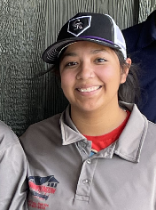 A woman wearing a baseball cap and a polo shirt is smiling.