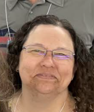 A close up of a woman wearing glasses and smiling.