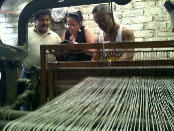 Two men and a woman are looking at a loom