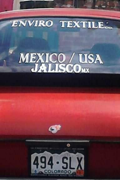 A red car with a sticker on the windshield that says enviro textile