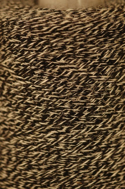 A close up of a spool of brown and white yarn.