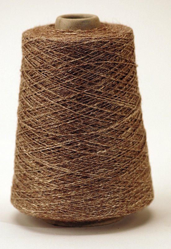 A spool of brown yarn is sitting on a white surface.