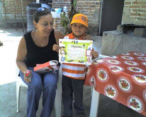 A woman sits next to a young boy holding a certificate that says ' 122 ' on it