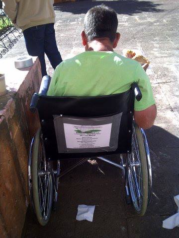 A man in a green shirt is sitting in a wheelchair