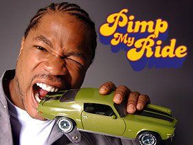 A man is holding a green toy car in front of a sign that says pimp my ride