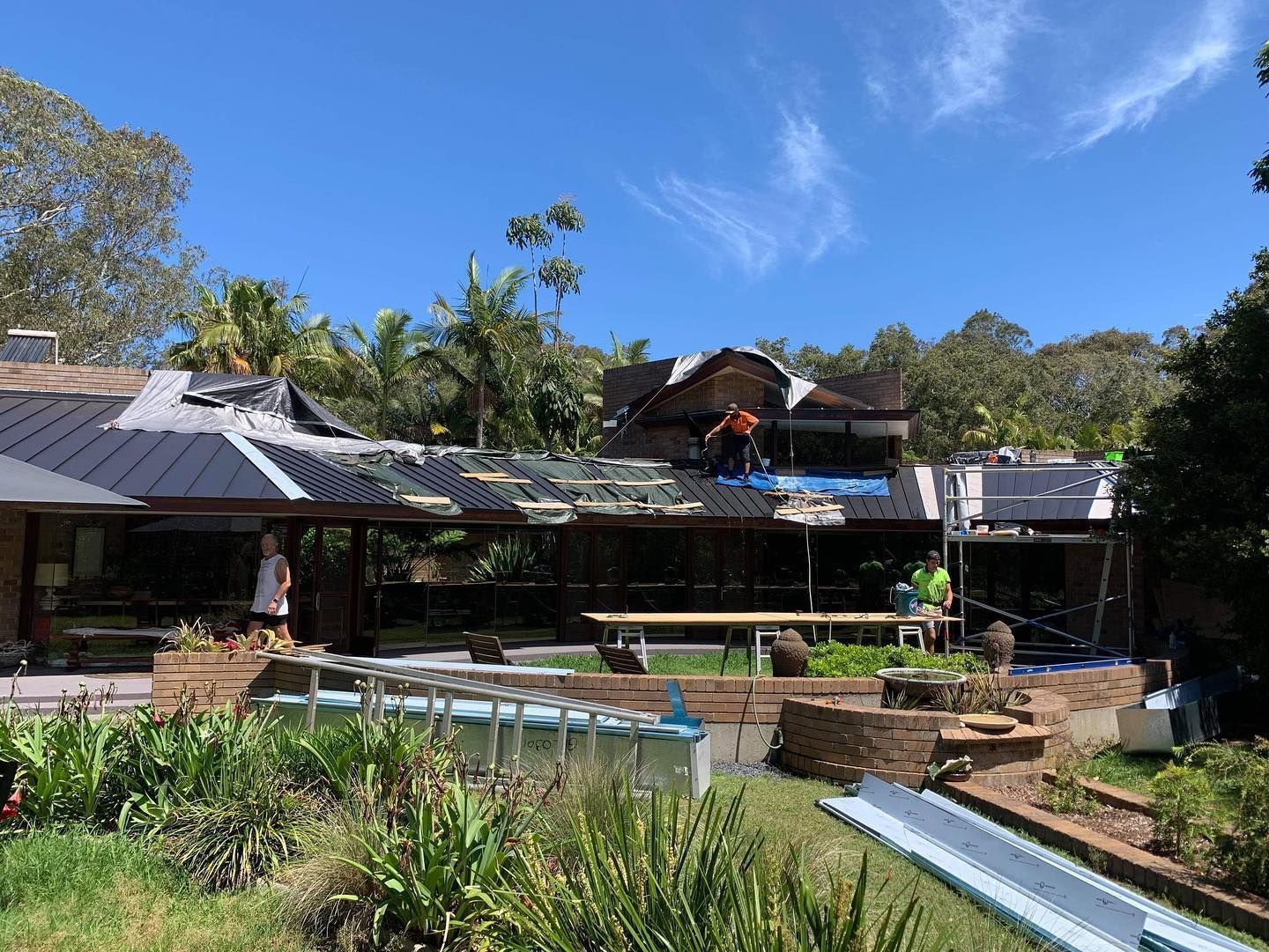 A Man is Working on the Roof of a House — Rhythm Roofing in Nambucca Heads, NSW