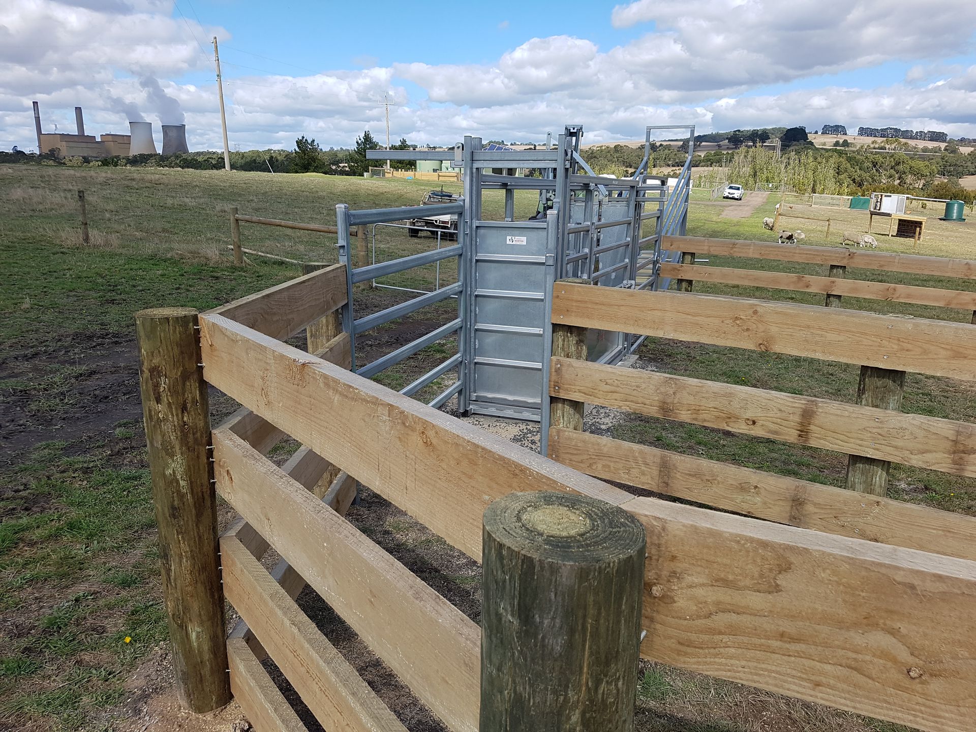 Wooden livestock fencing and metal gates in a rural field under a cloudy sky