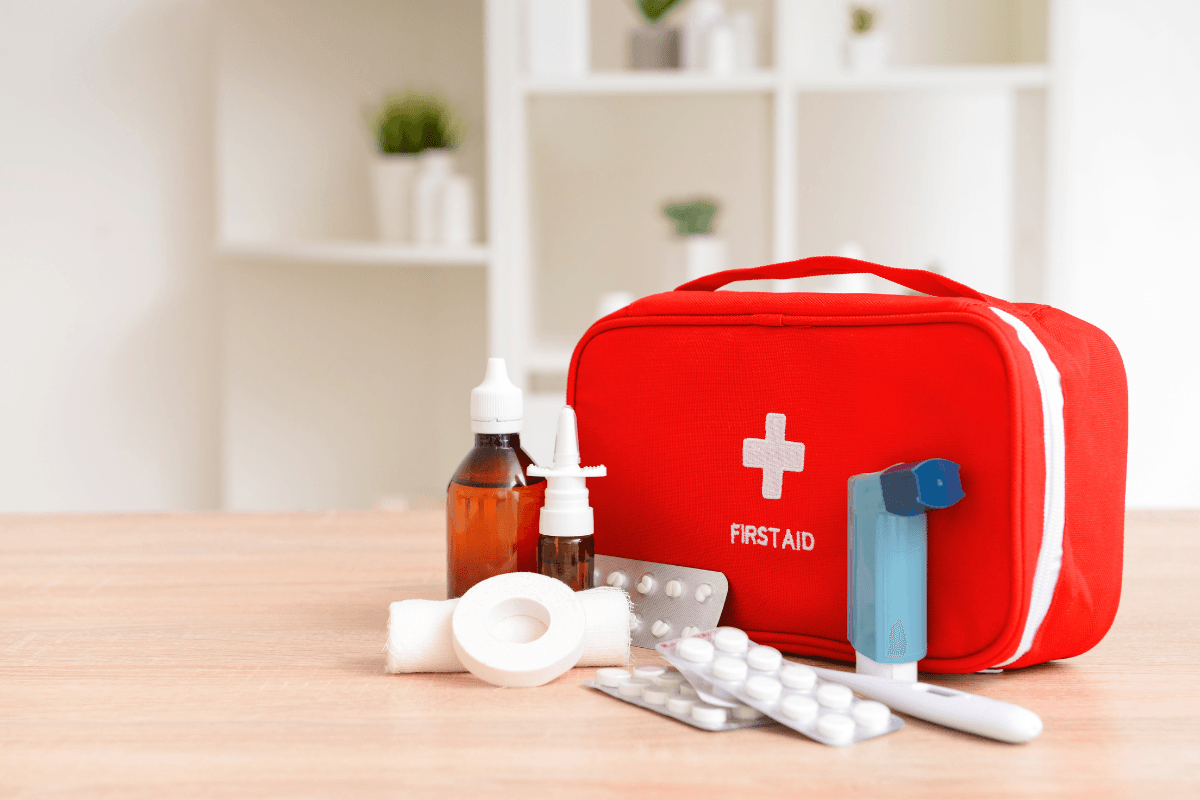 A red first aid kit is sitting on a wooden table.