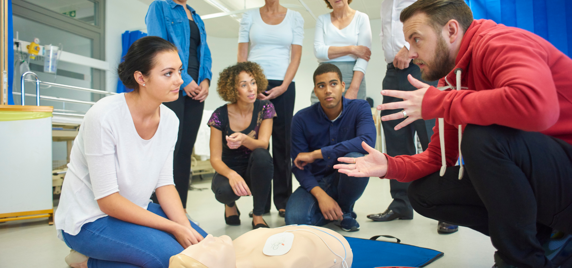 CPR training session with instructor demonstrating chest compressions on a manikin to a group
