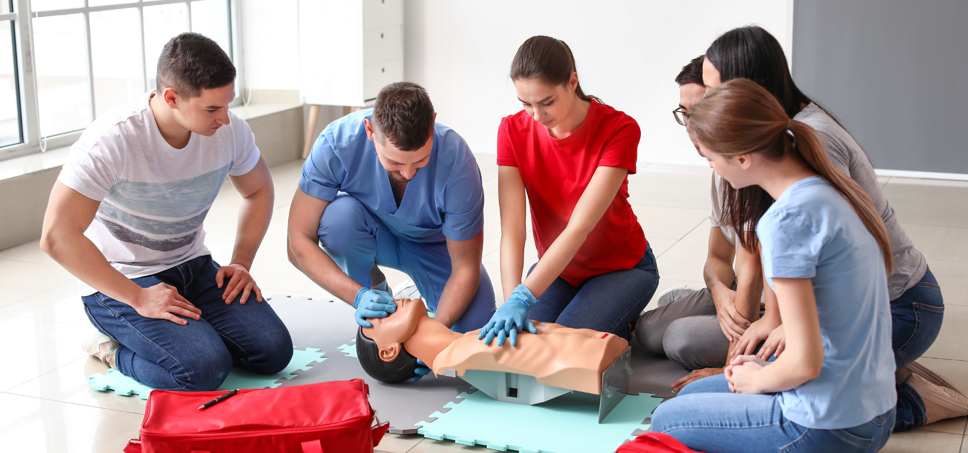 Four people kneel on a floor, assembling a puzzle with blue gloves and red and blue sheets nearby