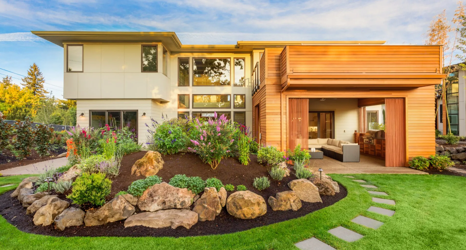 Modern house with landscaped front yard, stone path, and warm wooden entryway at sunset