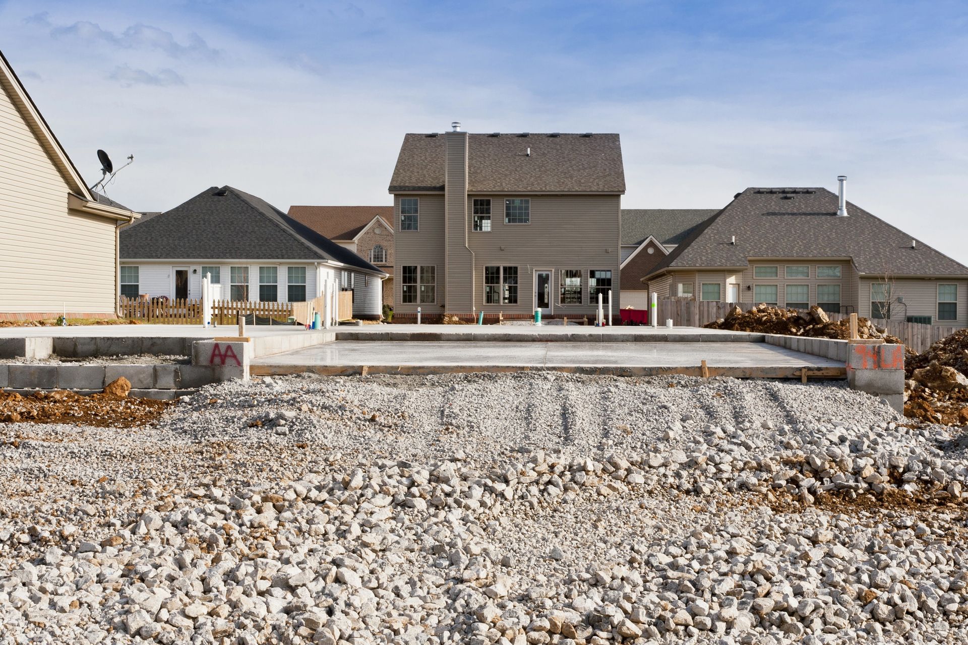 Gravel lot leading to modern suburban houses under a cloudy sky