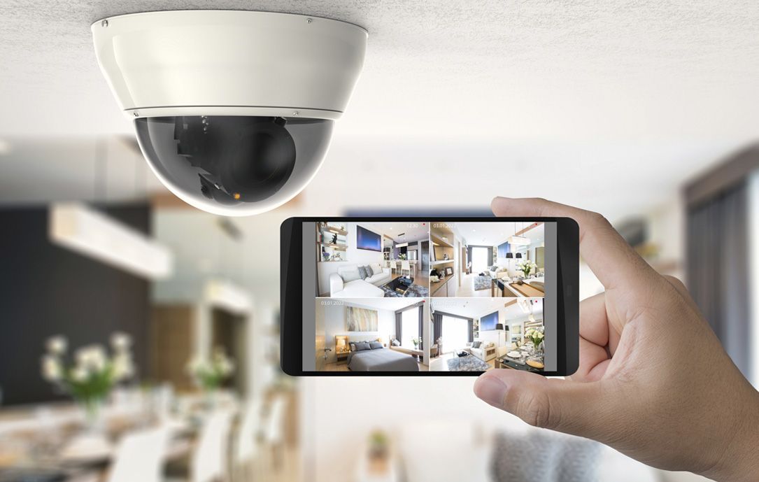 Telecamera di sicurezza in alto, telefono in mano che mostra video in diretta delle stanze.