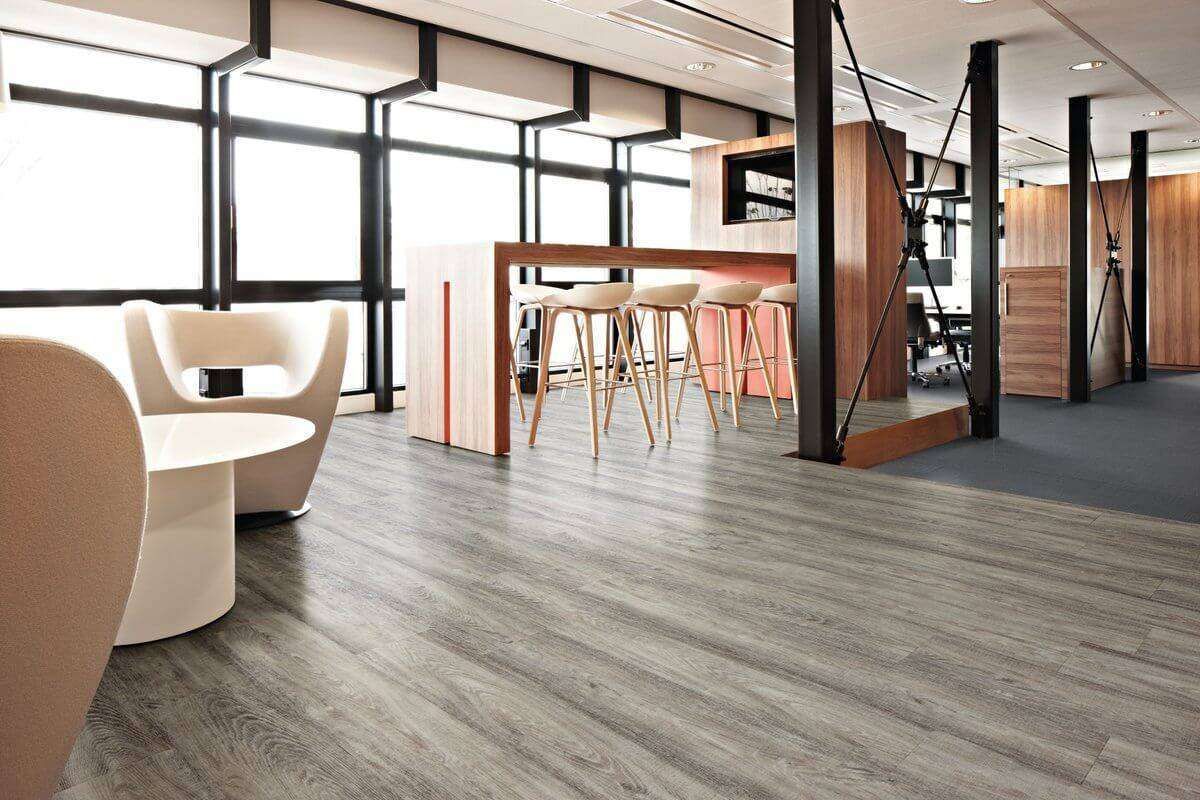 Modern office with wood flooring, bar, chairs, and large windows.