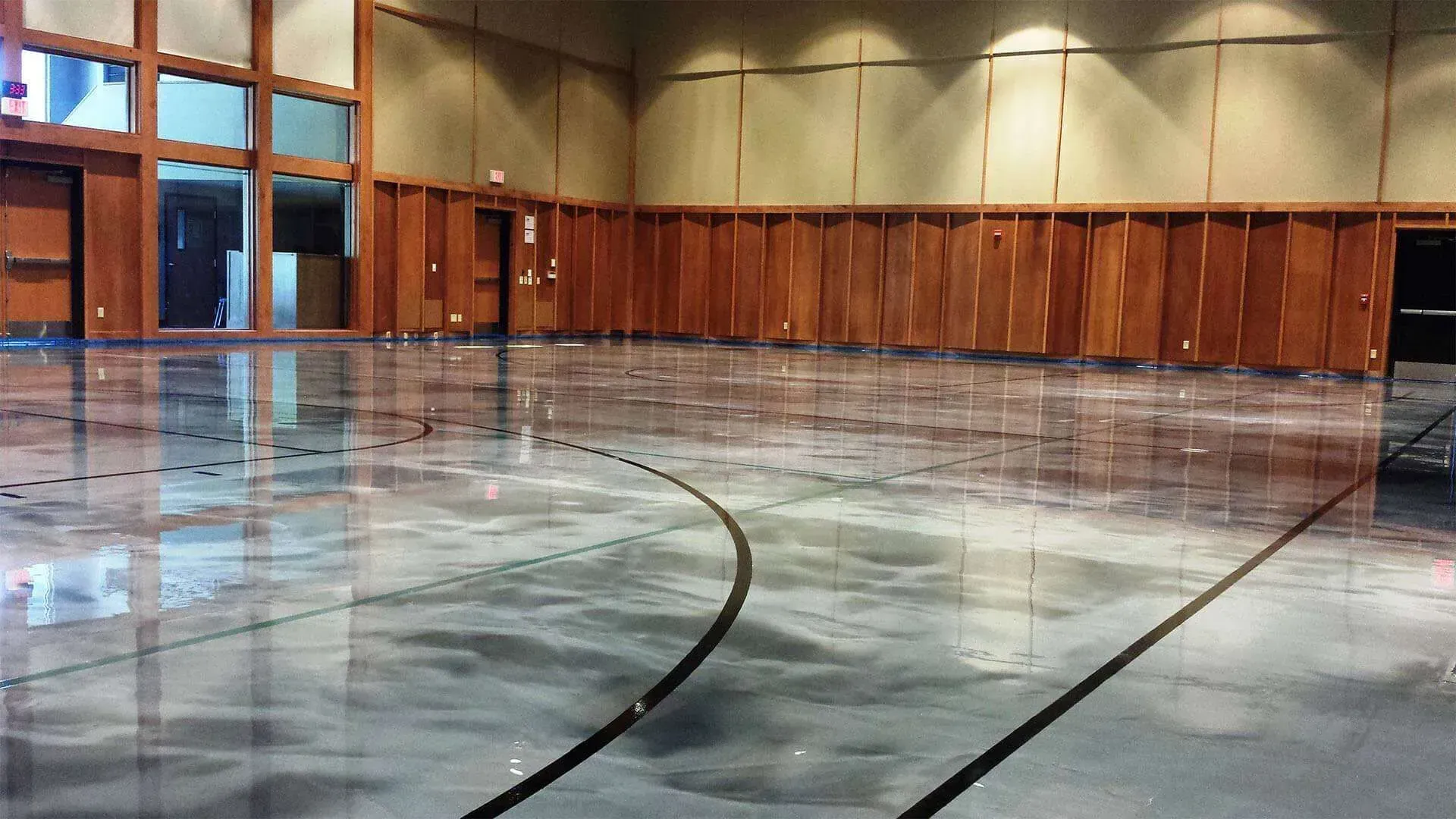 Shiny concrete floor with black lines, wooden walls, large windows. Empty room.