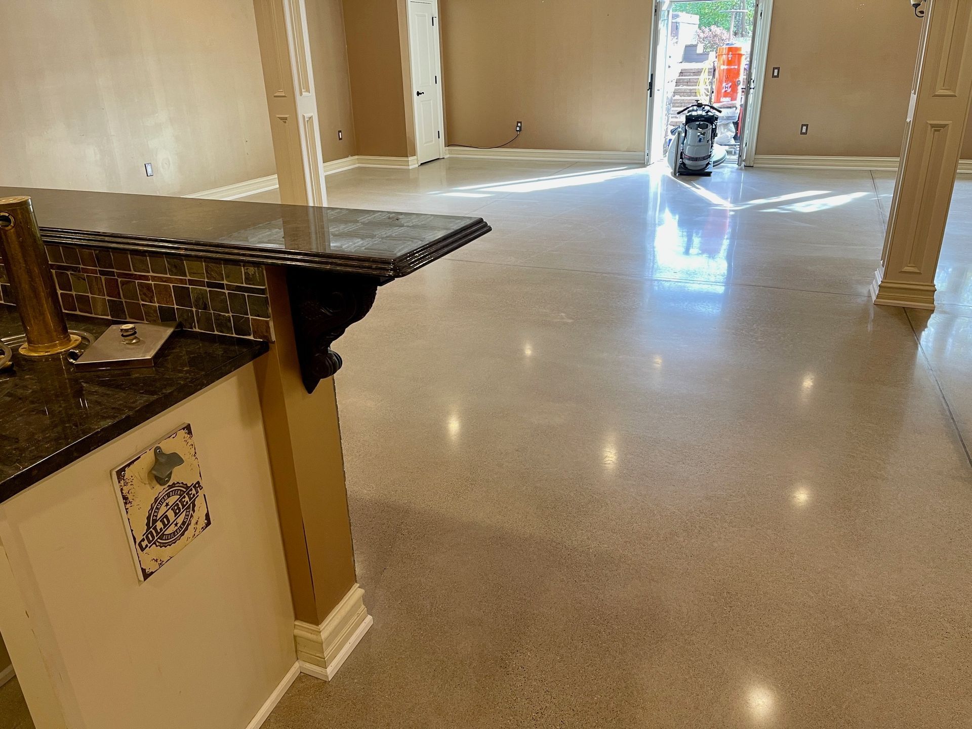 Polished concrete floor in a remodeled interior with a kitchen bar and an open doorway.