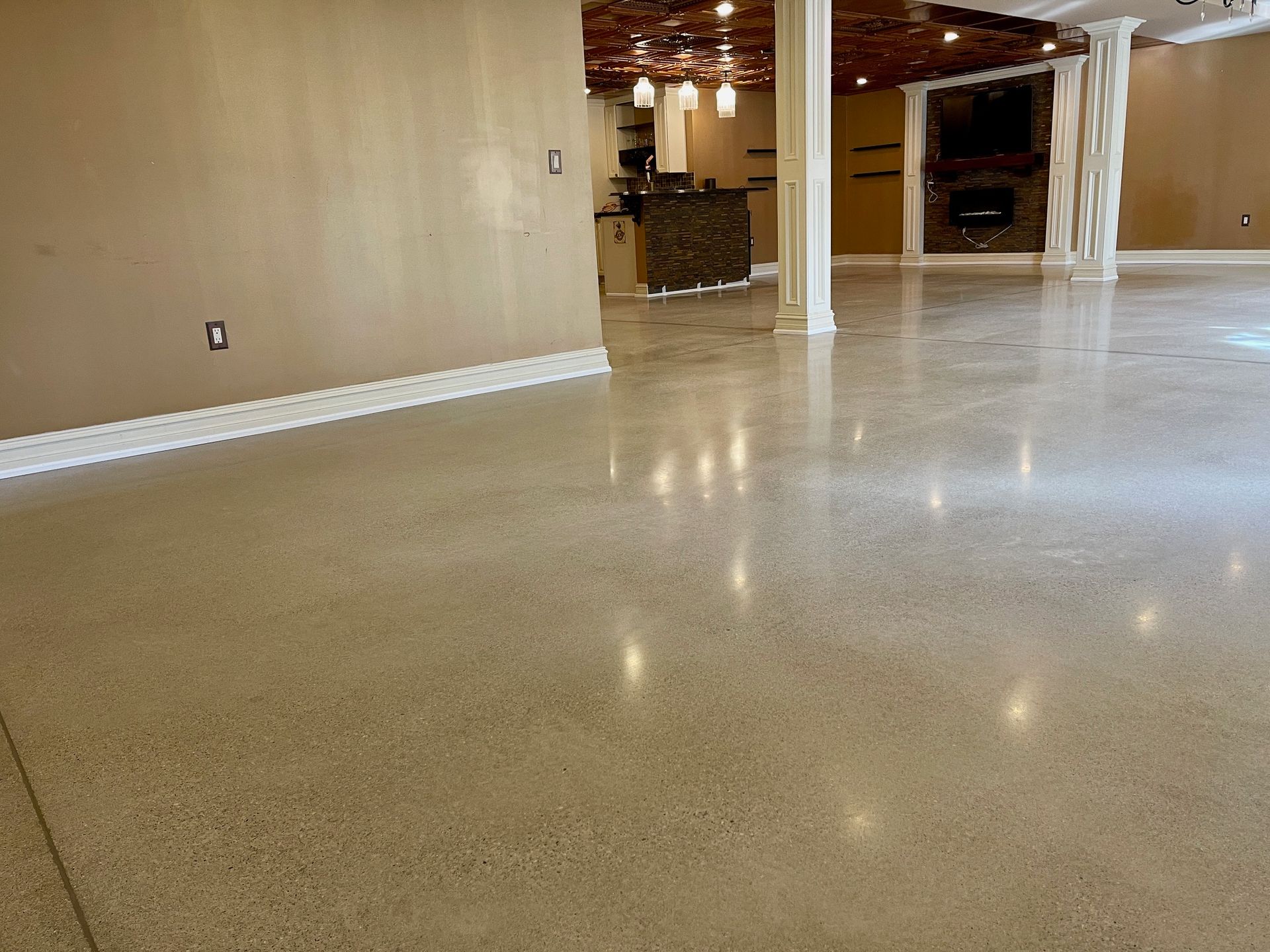 Polished concrete floor in a modern open space with tan walls, white trim, and support columns.