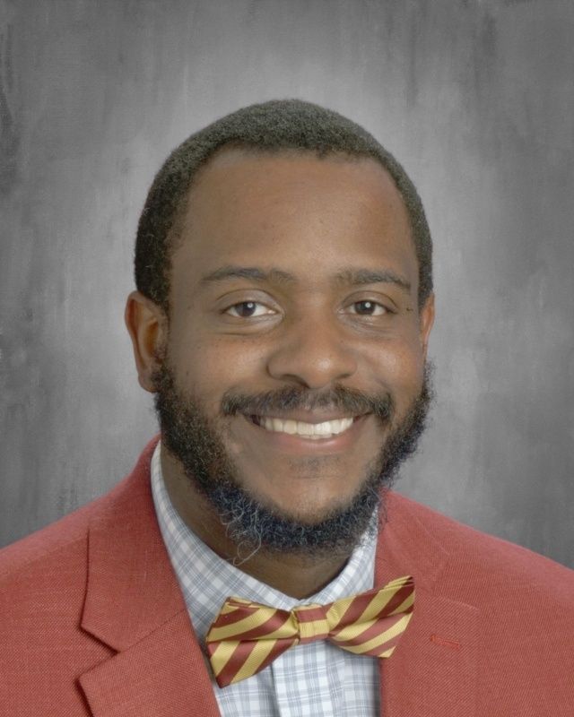 Smiling Black man in red blazer and striped bow tie.