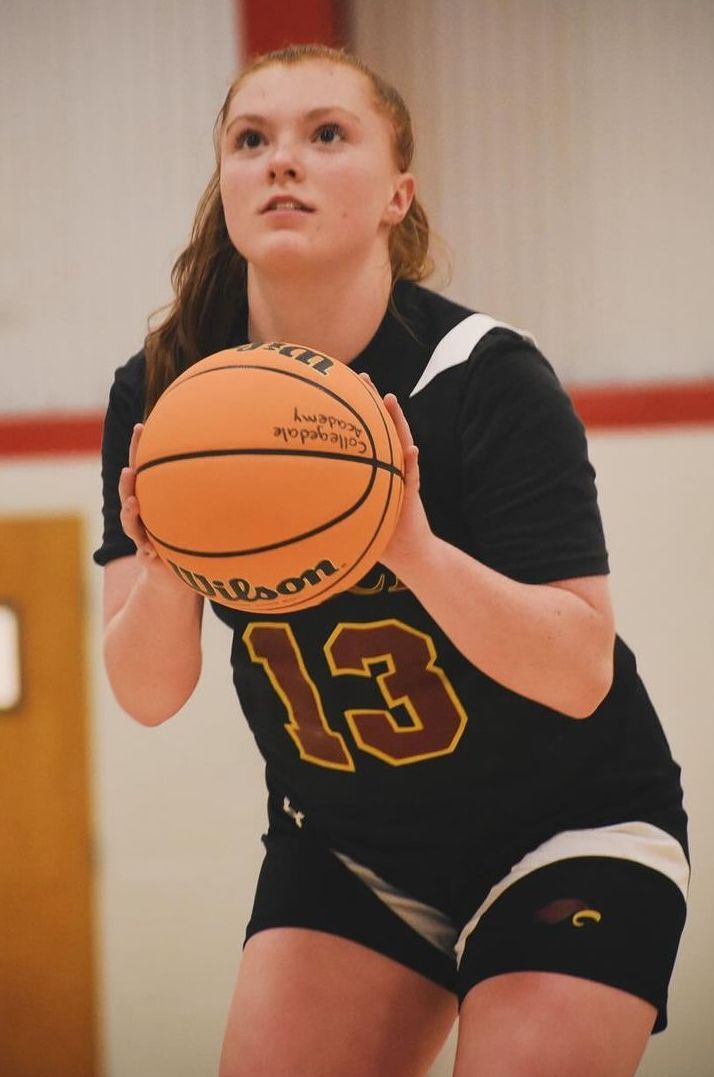 Female basketball player in black jersey with the number 13, holding the ball, focused gaze, preparing to shoot.