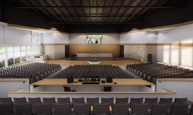 Auditorium with rows of seats facing a stage with a screen; a sound booth in the foreground.