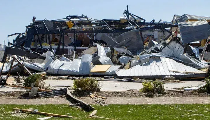 Destroyed building with debris scattered on the ground after a severe weather event.