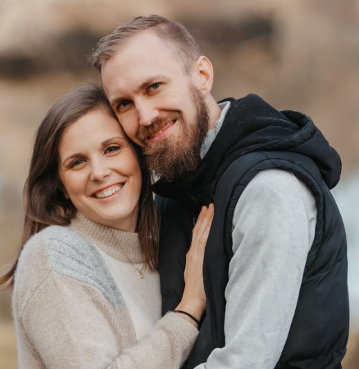 Woman and man embracing and smiling outdoors.
