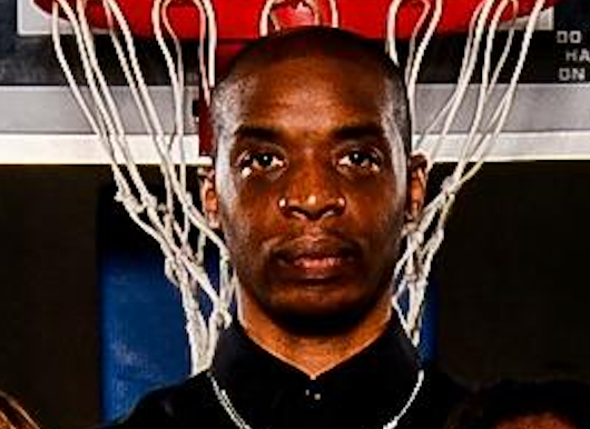 Man standing in front of a basketball net, wearing a black shirt.