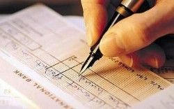 Hand writing on a check with a black pen; a person writing on a bank check.