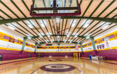 Basketball court inside a gymnasium; maroon and gold school colors.