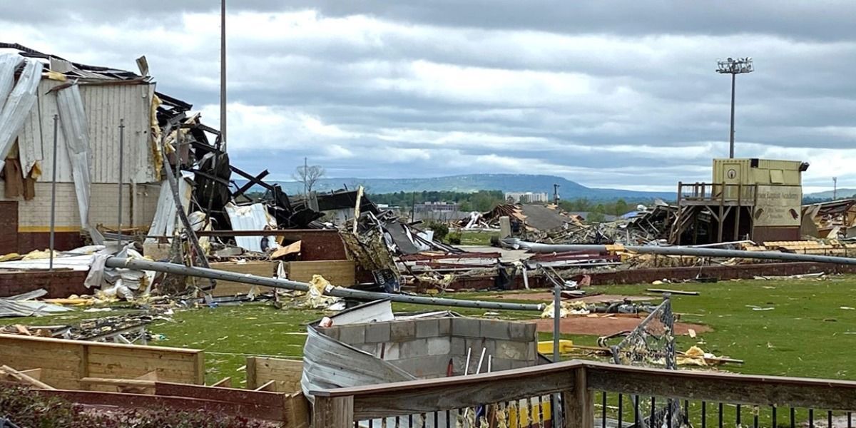 A landscape showing extensive destruction, possibly from a storm. Debris is scattered, and structures are damaged.