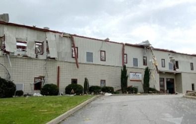 Building with significant damage, likely from a storm. Exterior shows torn siding and missing roof sections.