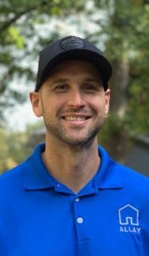 Man wearing a black hat and blue polo shirt with the word