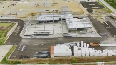 Construction site, aerial view. Steel framework of a building under construction, surrounded by materials and groundwork.