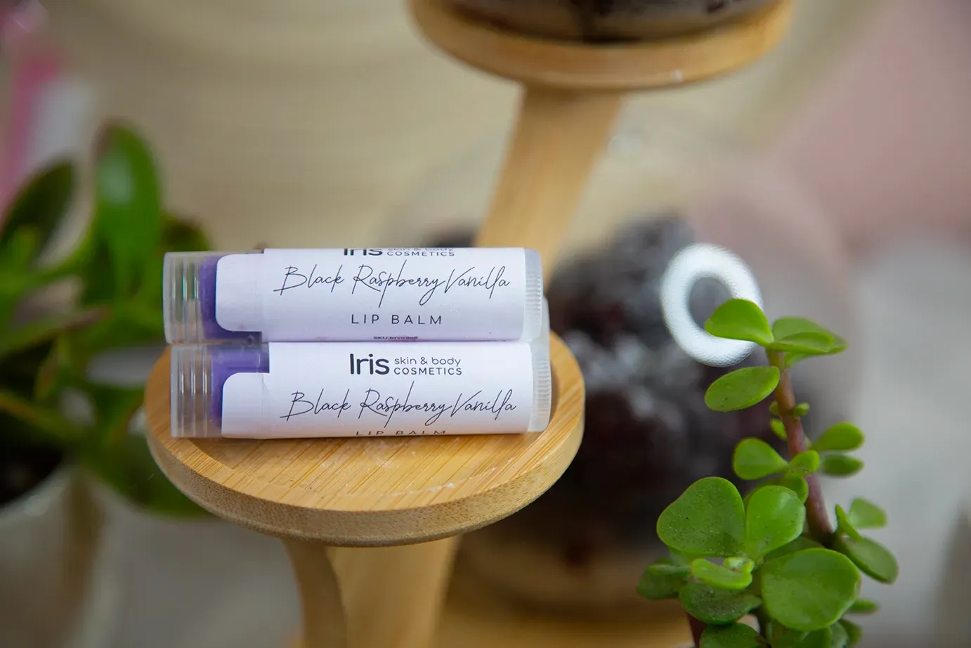 Two lip balms are stacked on top of each other on a wooden stand.
