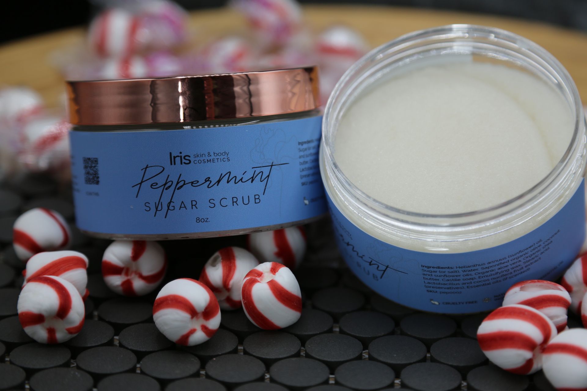 A jar of peppermint sugar scrub is surrounded by peppermint candies.