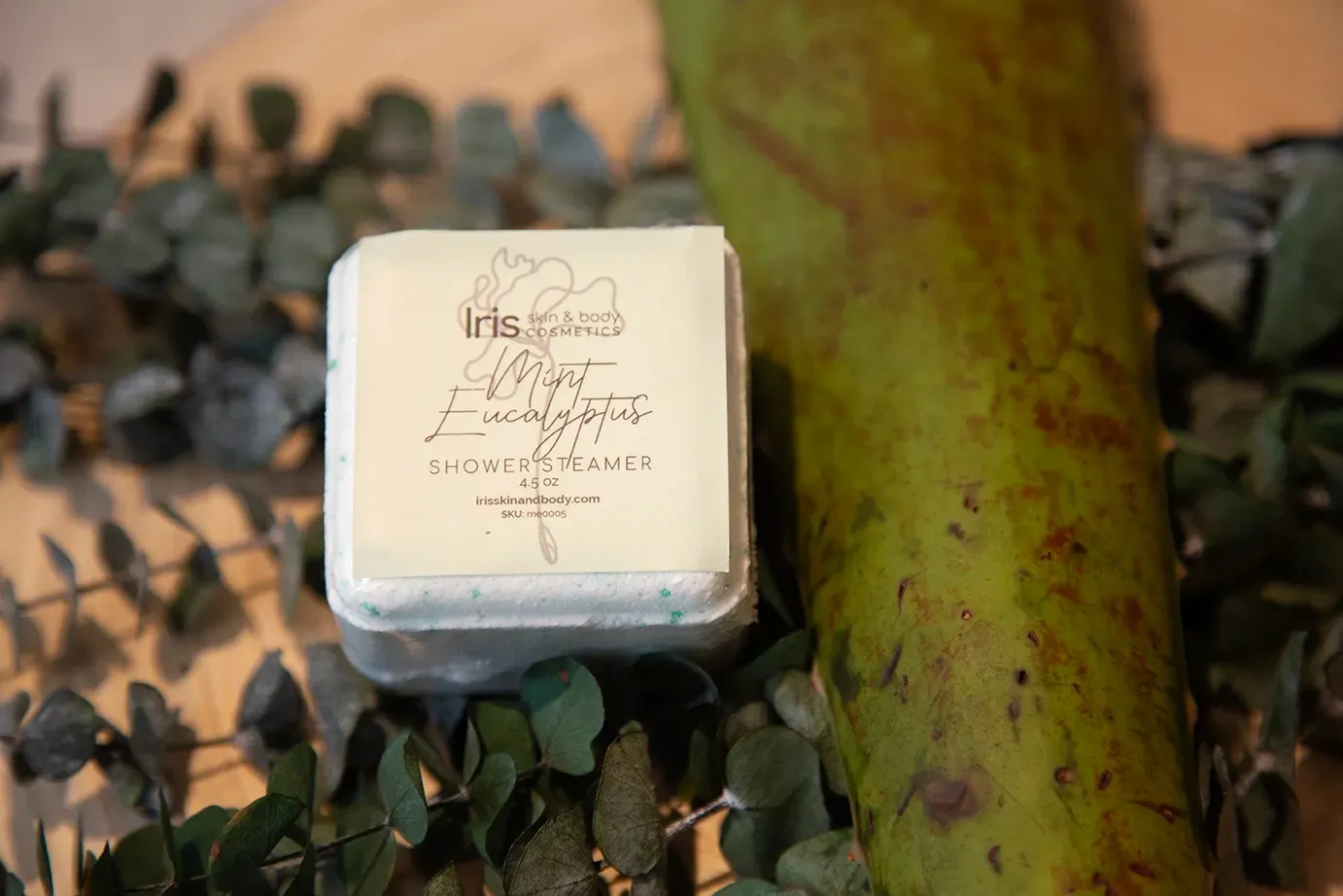 A box of soap is sitting on top of a pile of eucalyptus leaves.