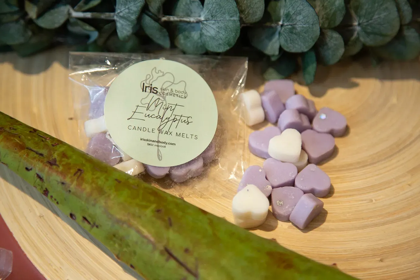 A bag of purple and white heart shaped wax melts on a wooden table.