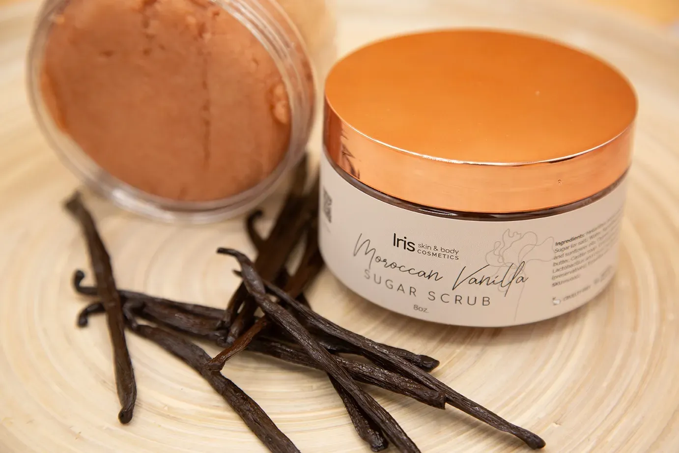 A jar of vanilla sugar scrub next to some vanilla beans