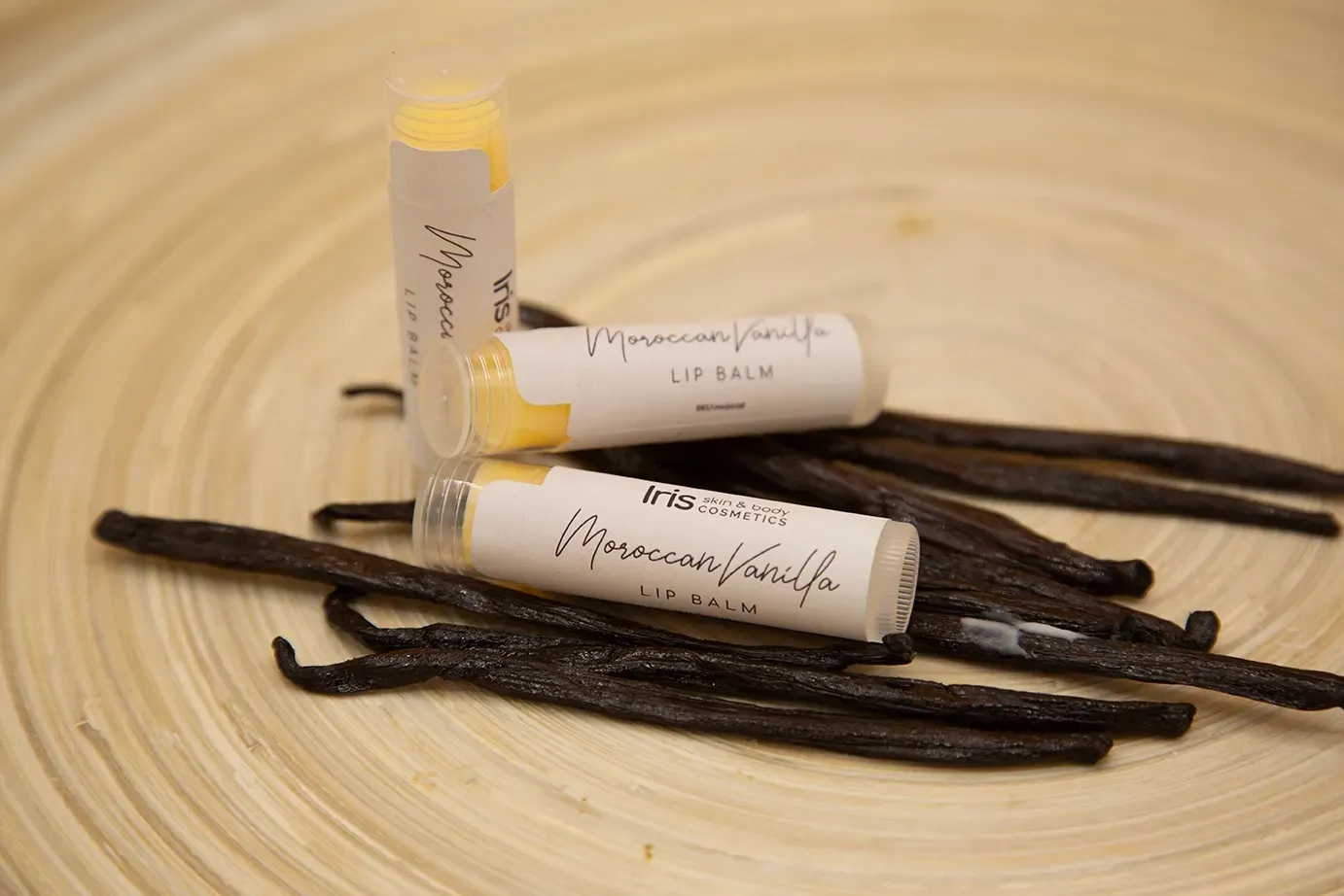 Vanilla sticks and lip balm on a wooden plate