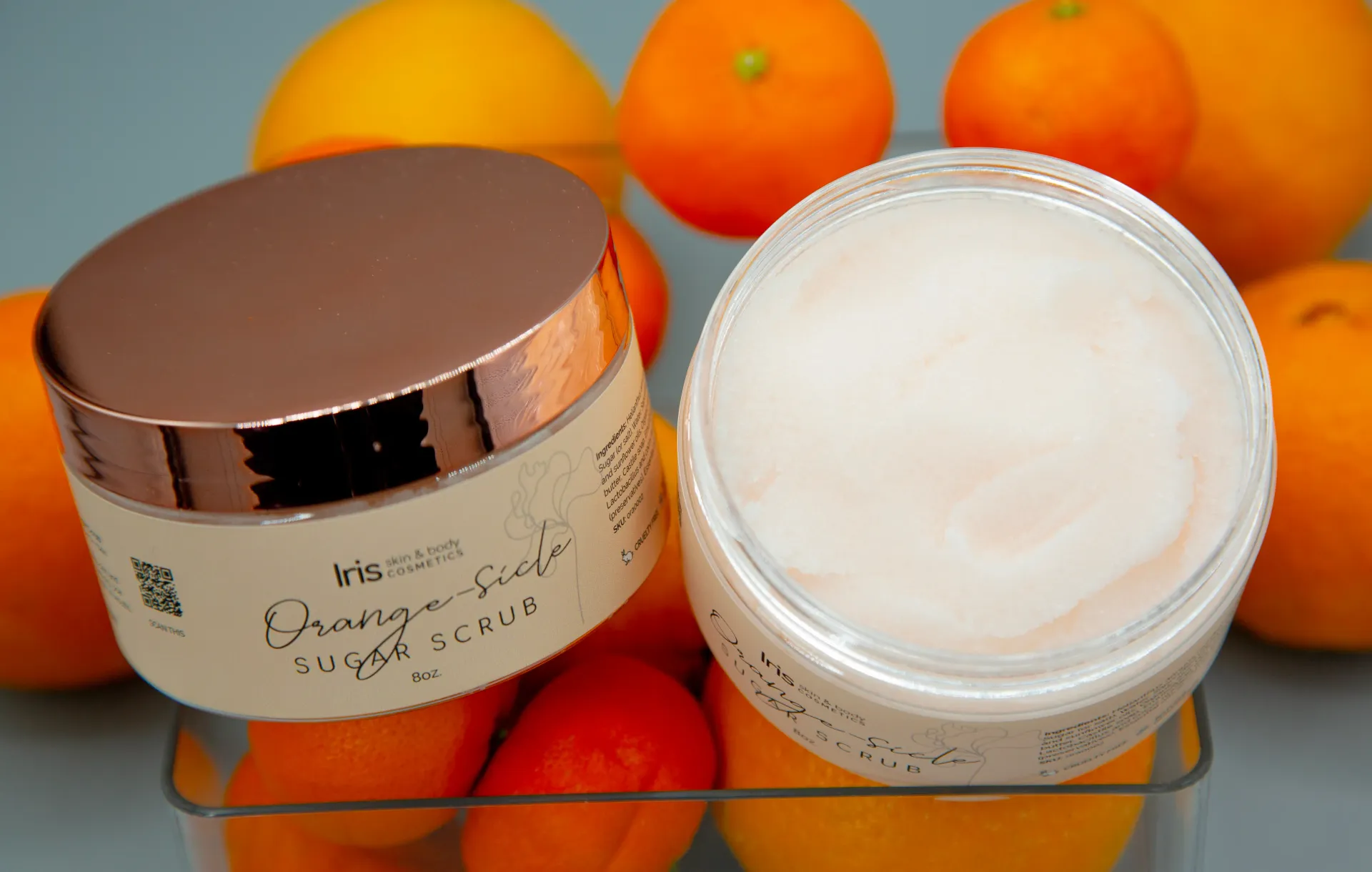 A jar of lotion sits in front of oranges